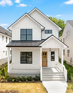 a view of a white house with large windows and a small yard