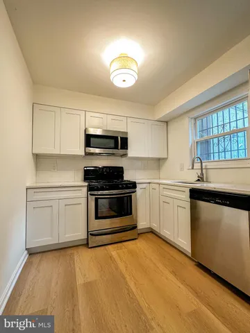 a kitchen with stainless steel appliances a stove a sink cabinets and a window