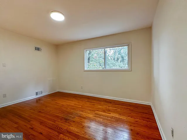 an empty room with wooden floor and window