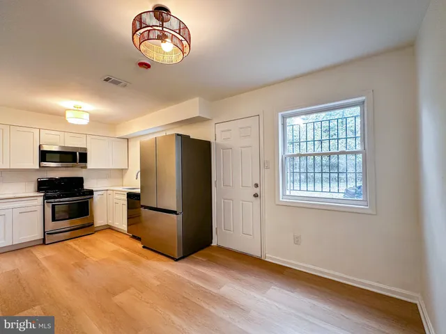 a kitchen with stainless steel appliances granite countertop a refrigerator oven a sink dishwasher and a stove with wooden floor