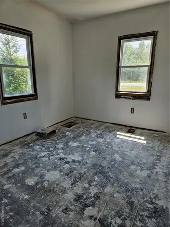 a view of an empty room with wooden floor and windows