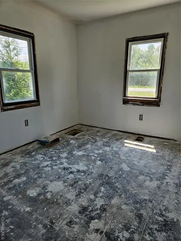 a view of an empty room with wooden floor and windows