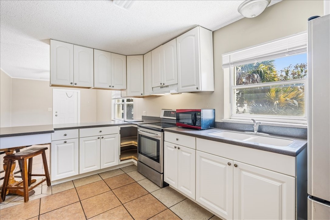 221 Balboa Street, Unit A Fort Pierce, FL 34949 - Photo 25 of 36 a kitchen with granite countertop white cabinets window and sink
