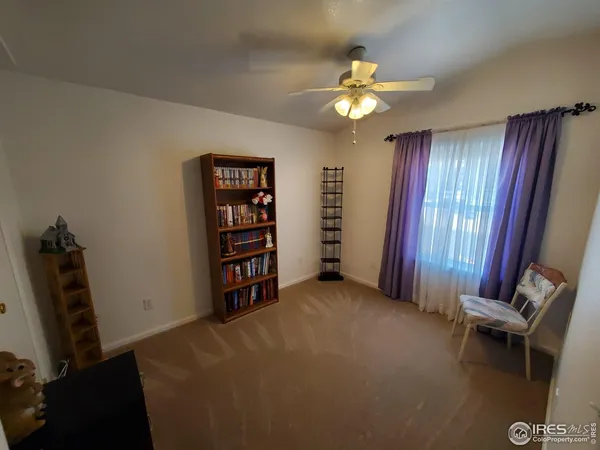 a view of an empty room with windows and chandelier fan
