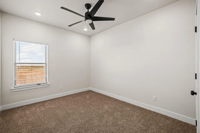 an empty room with a window and a fan