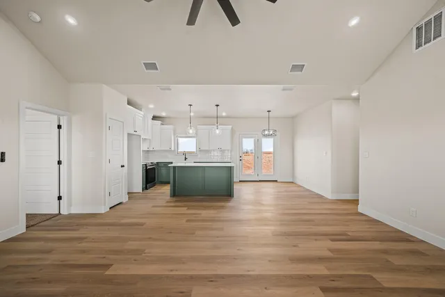 a view of large kitchen with kitchen island a island wooden floor stainless steel appliances and cabinets