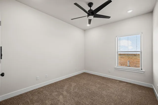 an empty room with a window and a fan