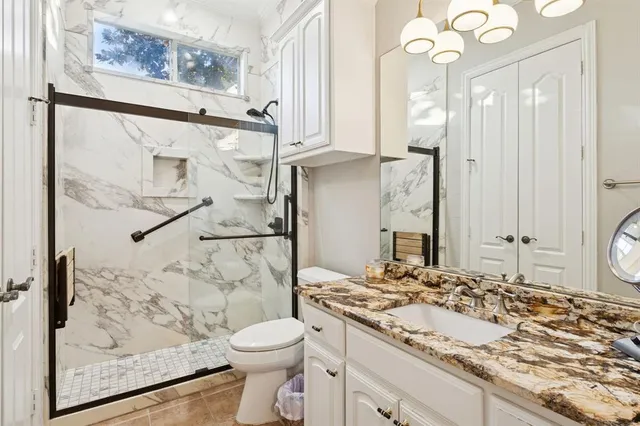 a bathroom with a granite countertop sink mirror vanity and toilet