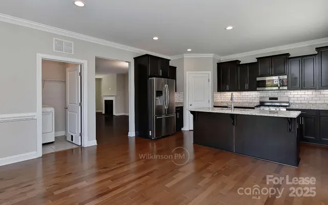 a kitchen with stainless steel appliances kitchen island granite countertop a refrigerator and a stove top oven