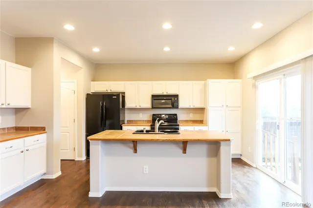 a room with kitchen island granite countertop stainless steel appliances a sink and a refrigerator