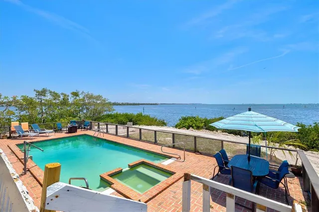 a view of a swimming pool with lawn chairs under an umbrella