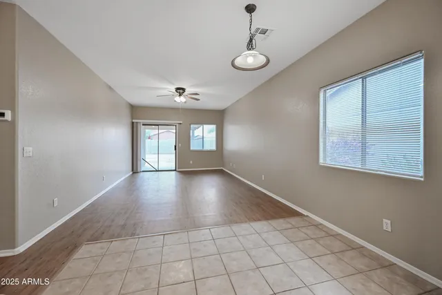 a view of an empty room with window and chandelier fan