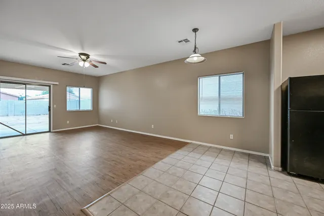 an empty room with windows and chandelier fan