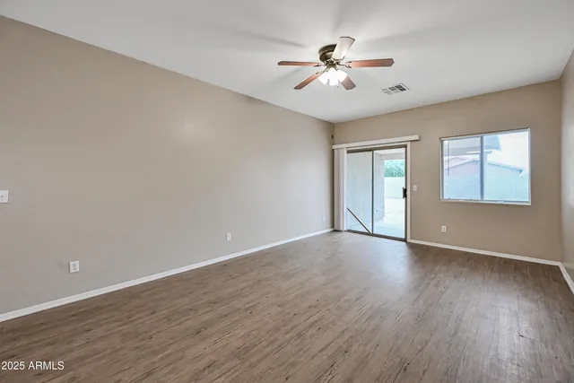 a view of an empty room with a chandelier fan and wooden floor