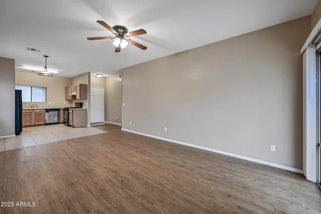 a view of an empty room with a window and wooden floor