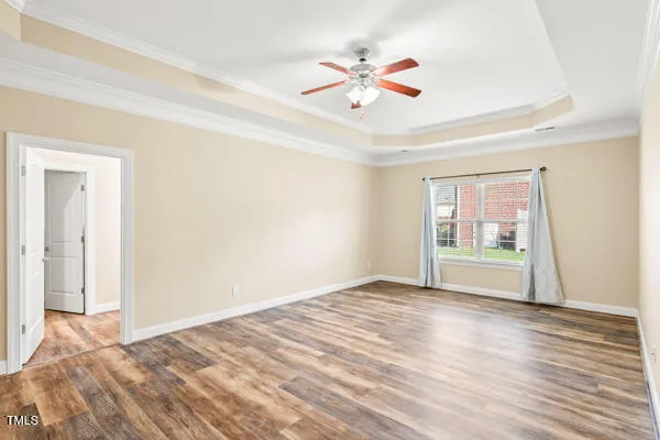 a view of an empty room with wooden floor and a ceiling fan