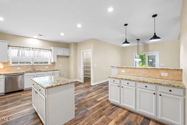 a kitchen with granite countertop cabinets stainless steel appliances and a wooden floor