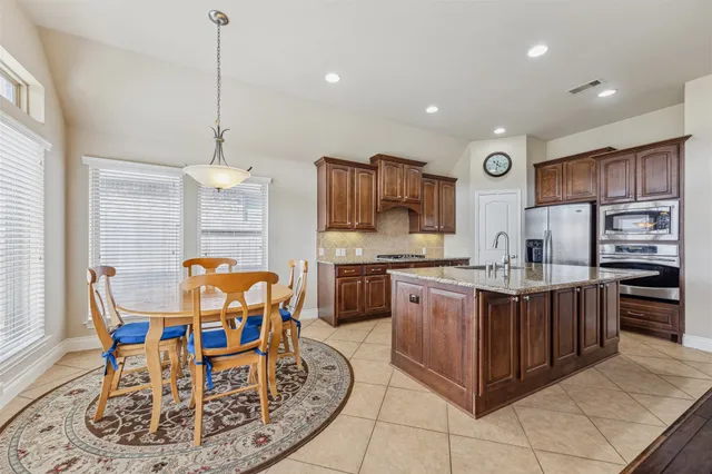 a kitchen with stainless steel appliances granite countertop a kitchen island a stove a refrigerator and a sink