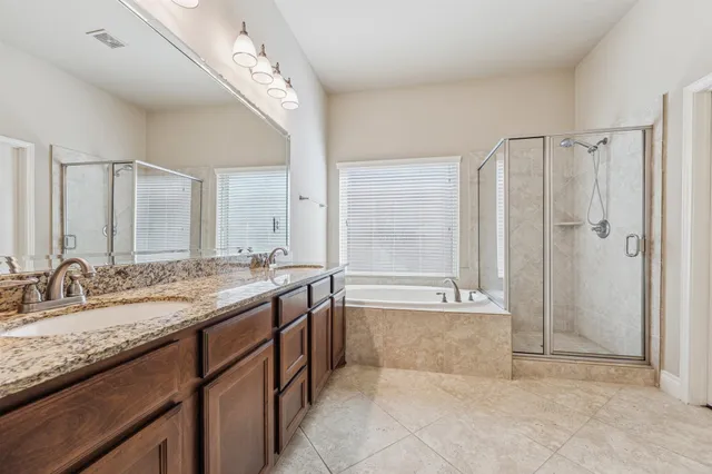 a bathroom with a granite countertop bathtub double sink and mirror
