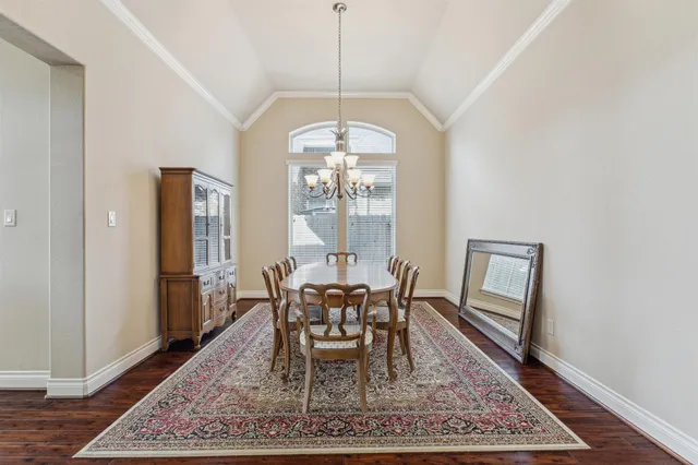 a dining room with wooden floor a rug and a chandelier