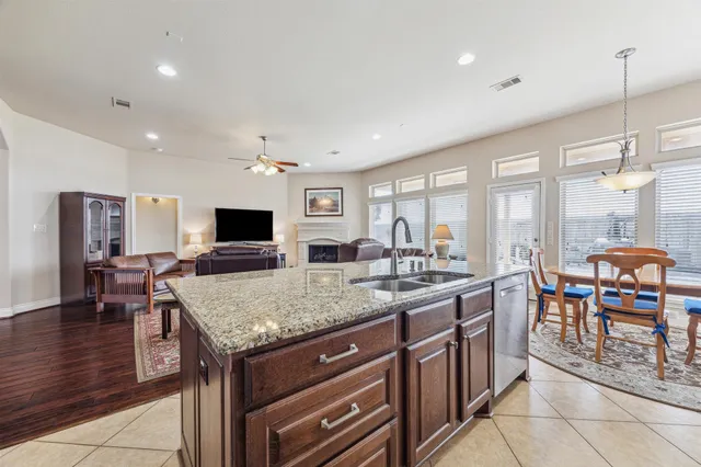 a kitchen with stainless steel appliances granite countertop a stove top oven a sink dishwasher a dining table and chairs with wooden floor