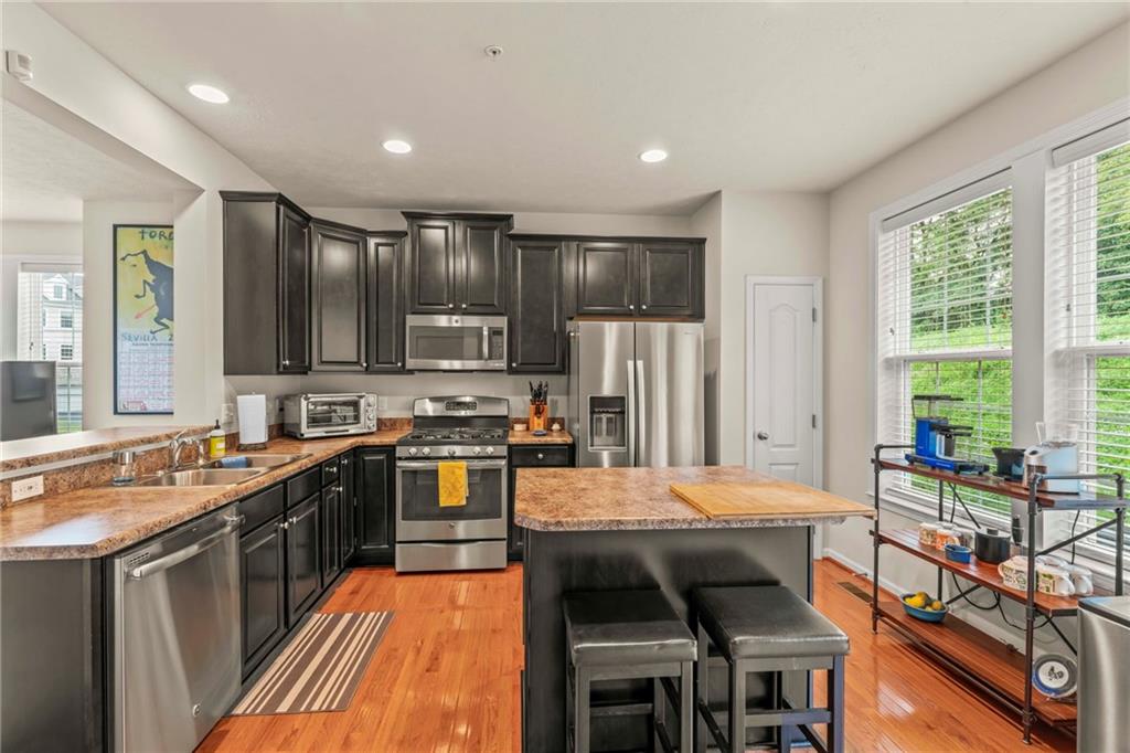 2 Truman Circle McKees Rocks, PA 15136 - Photo 7 of 26 a kitchen with stainless steel appliances granite countertop a stove top oven a sink dishwasher a dining table and chairs with wooden floor