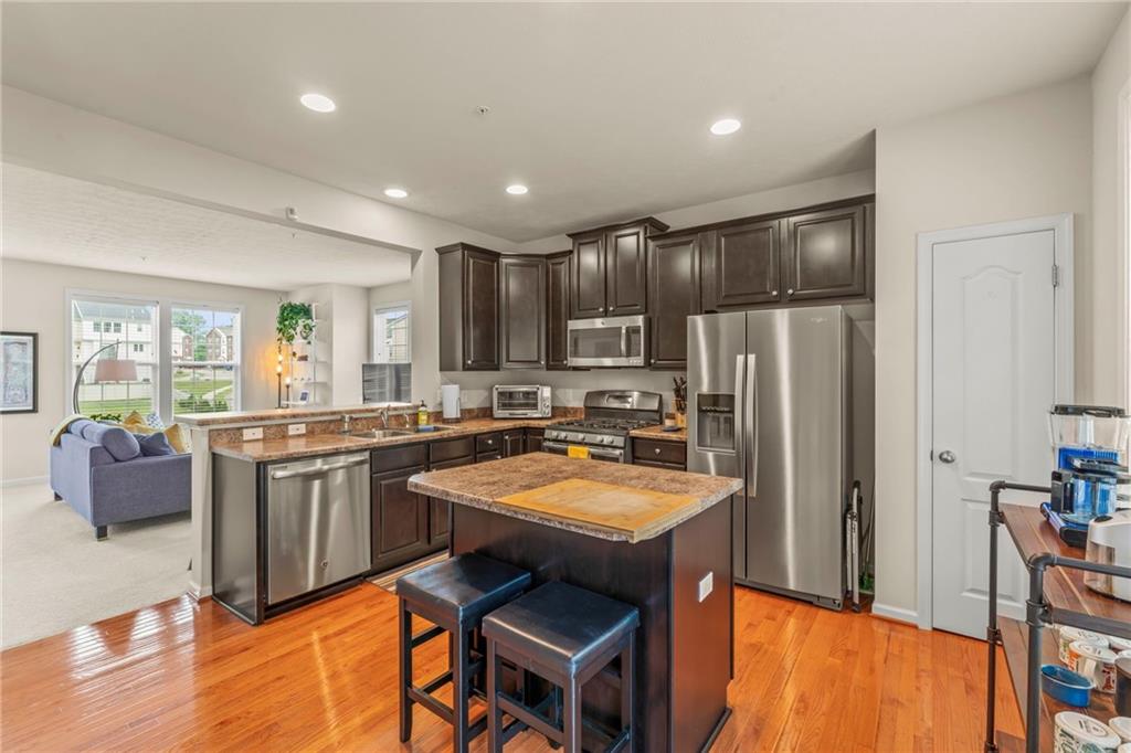 2 Truman Circle McKees Rocks, PA 15136 - Photo 8 of 26 a kitchen with stainless steel appliances granite countertop a refrigerator a sink dishwasher a stove a dining table and chairs with wooden floor