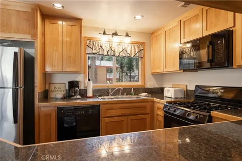 a kitchen with stainless steel appliances granite countertop a stove a sink dishwasher and a refrigerator with wooden floor