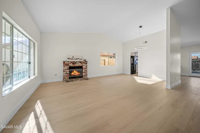 an empty room with windows and fireplace
