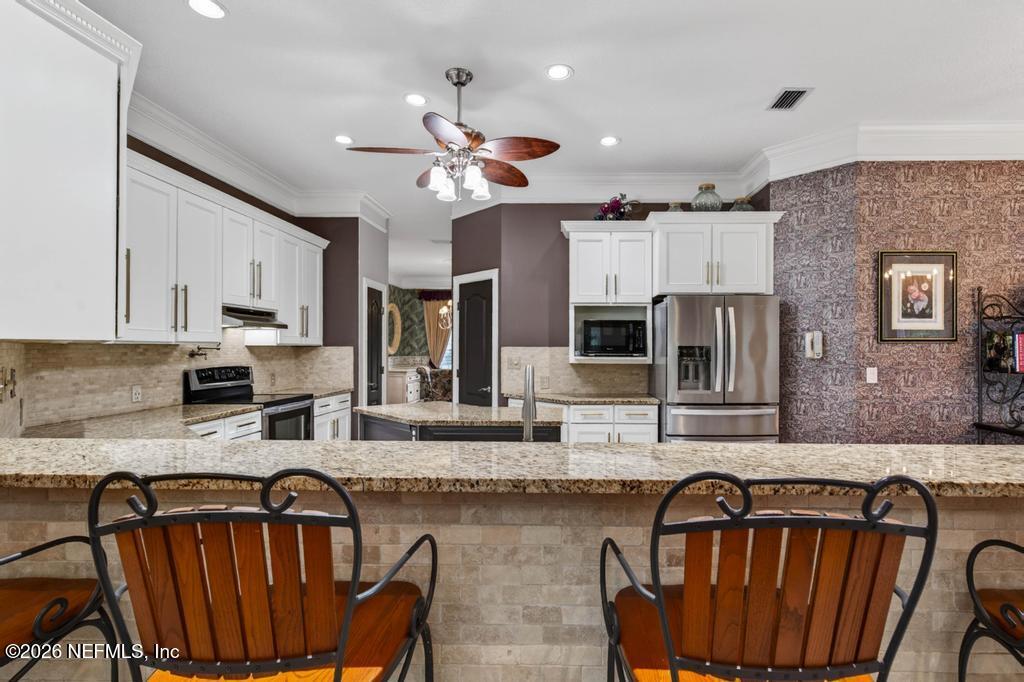1483 Bridgette Way Fleming Island, FL 32003 - Photo 28 of 63 a kitchen with granite countertop a stove a sink dishwasher a dining table and chairs with wooden floor