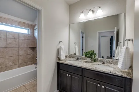 a bathroom with a granite countertop sink mirror and a bathtub