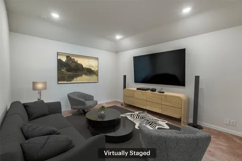 a living room with computer on a table and a book shelf