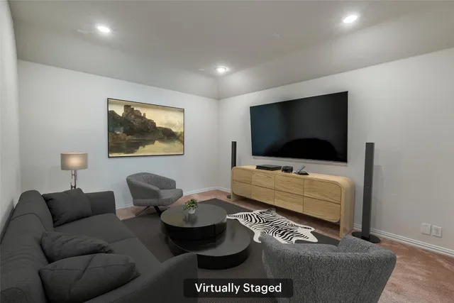 a living room with computer on a table and a book shelf