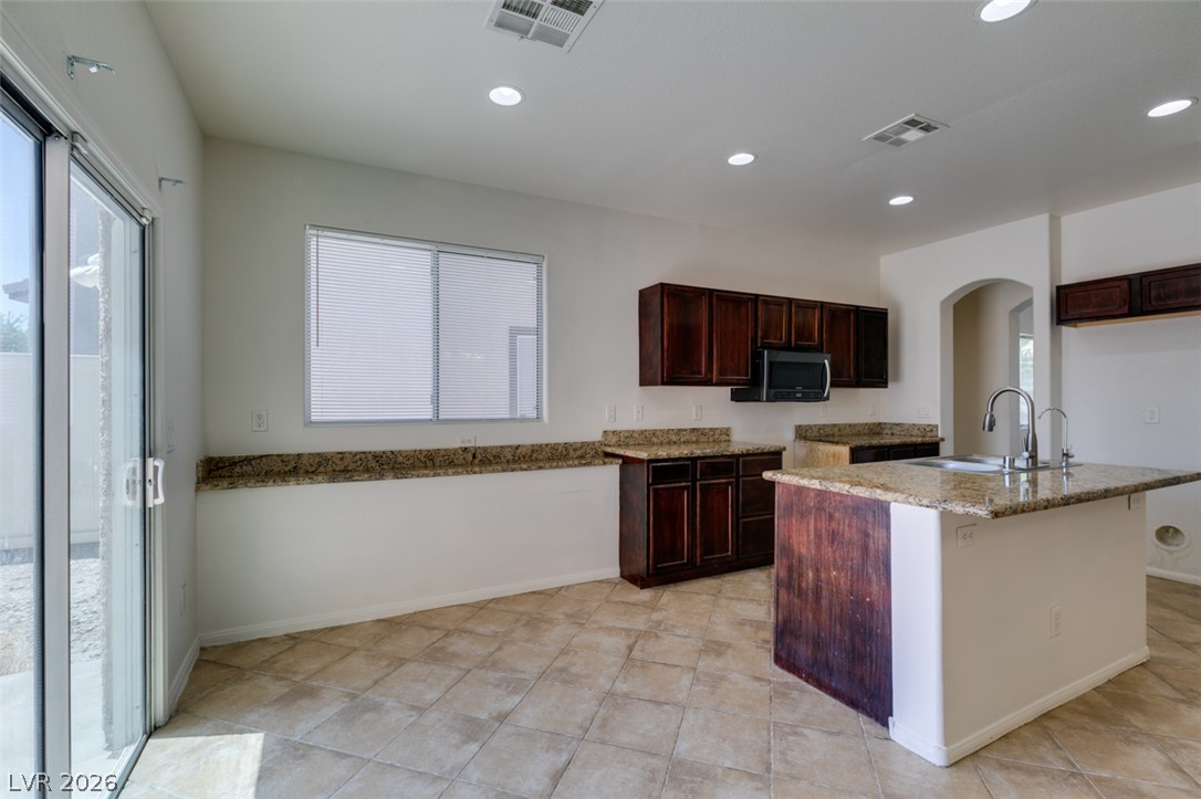 5150 Riverside Run Court North Las Vegas, NV 89081 - Photo 25 of 50 A well-appointed kitchen showcasing an island with a sink and rich granite countertops.