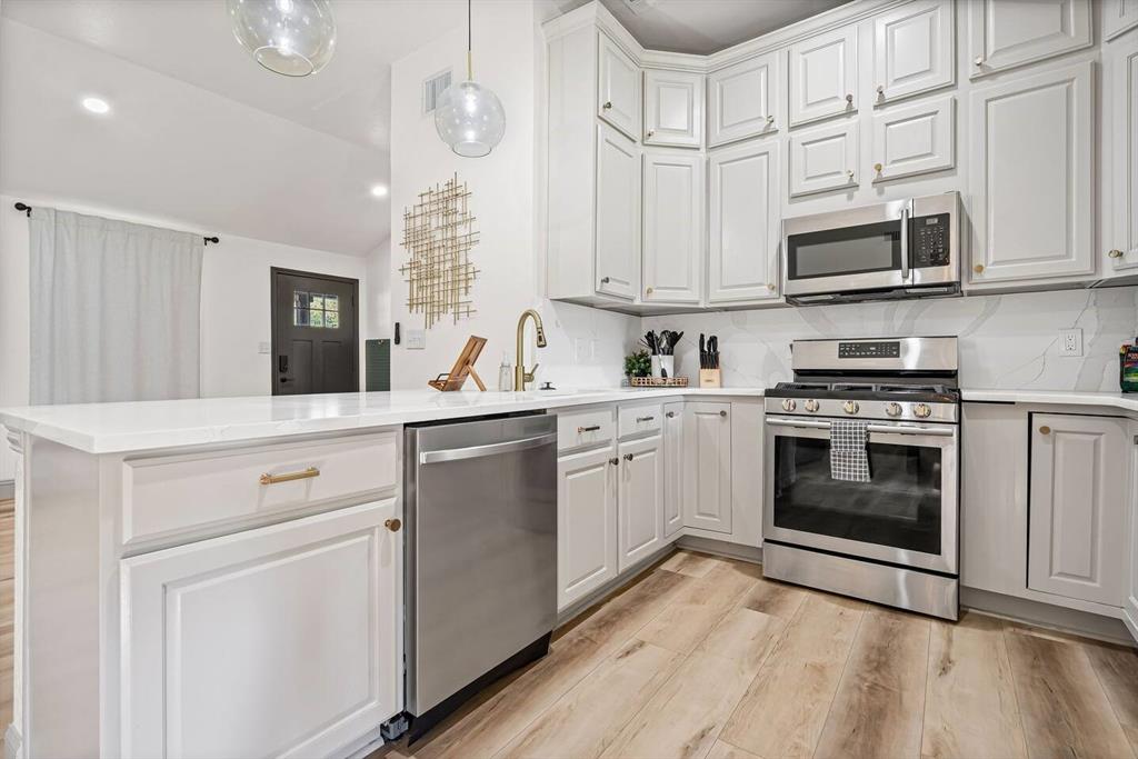 4918 Farris Road Denton, TX 76208 - Photo 12 of 28 a kitchen with stainless steel appliances granite countertop white cabinets a sink a stove a dining table and chairs