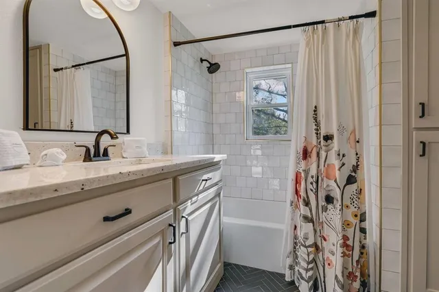 a bathroom with a granite countertop sink a mirror a shower and a bathtub