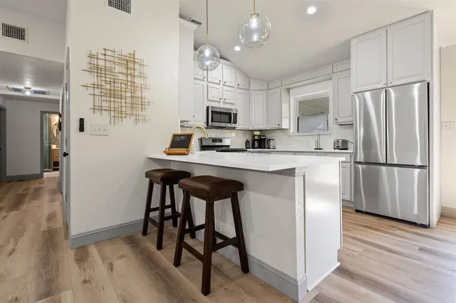 a kitchen with stainless steel appliances a refrigerator a sink dishwasher a stove and a refrigerator with wooden floor