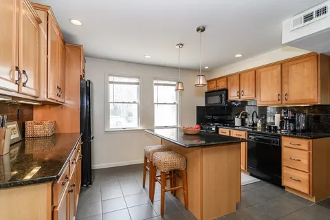 a kitchen with kitchen island granite countertop a sink appliances cabinets and furniture