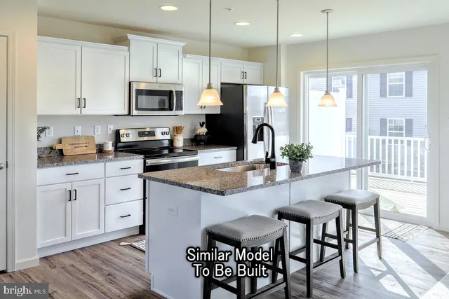 a kitchen with stainless steel appliances granite countertop a stove a sink a microwave a refrigerator and white cabinets