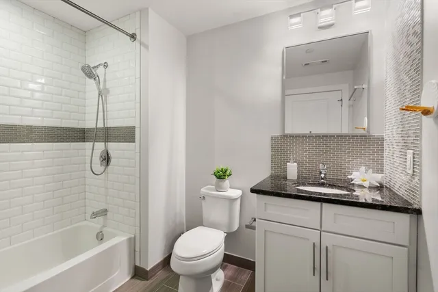 a bathroom with a granite countertop sink a toilet and shower