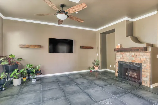 a living room with a fireplace furniture a potted plant and a ceiling fan