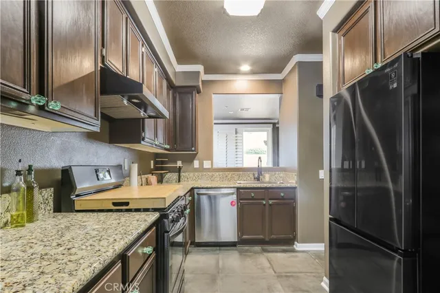 a kitchen with stainless steel appliances granite countertop a refrigerator a stove and a sink