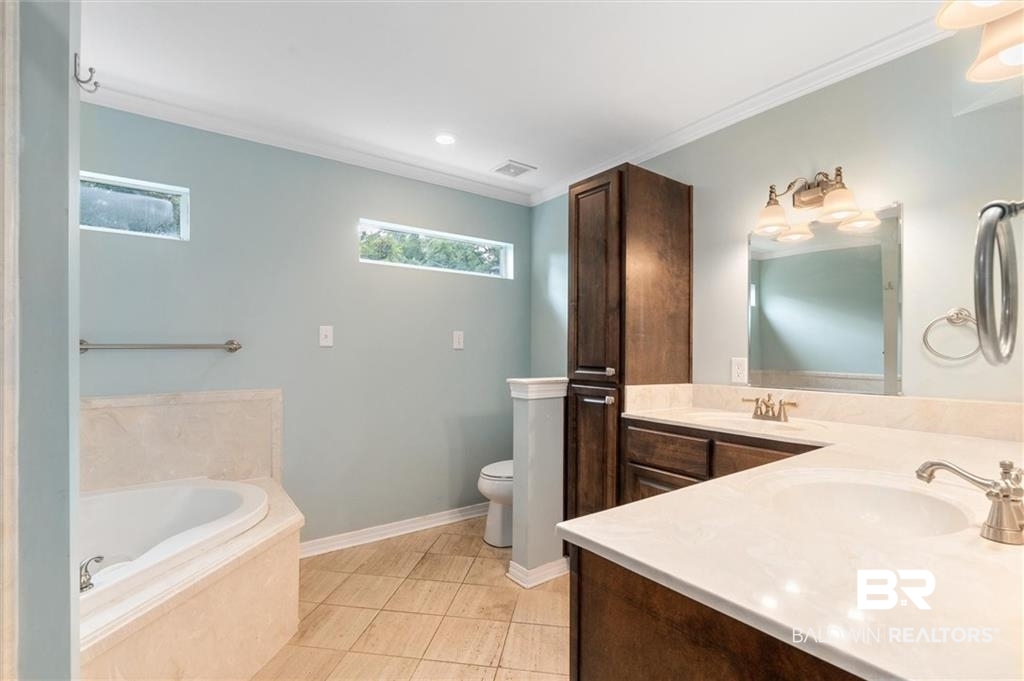218 Grand Boulevard Mobile, AL 36607 - Photo 11 of 22 Bathroom with toilet, tile patterned flooring, ornamental molding, tiled tub, and vanity