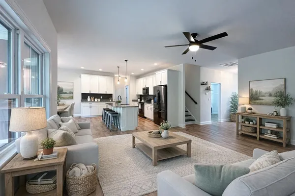 a living room with furniture kitchen view and a window
