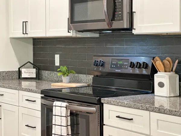a kitchen with granite countertop cabinets stove top oven and microwave