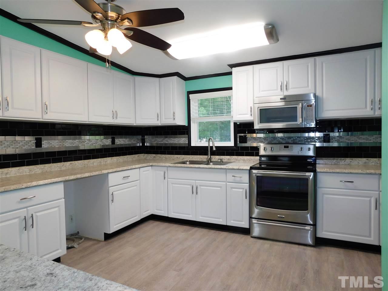 164 Clyde Pearce Road Zebulon, NC 27597 - Photo 4 of 25 a kitchen with stainless steel appliances granite countertop a stove a sink and a microwave