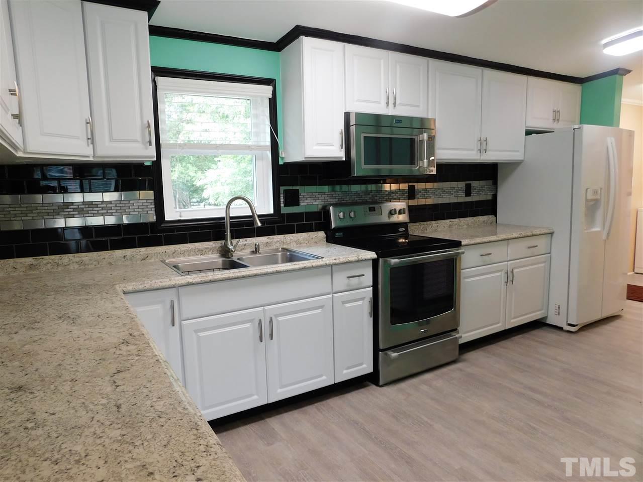 164 Clyde Pearce Road Zebulon, NC 27597 - Photo 5 of 25 a kitchen with stainless steel appliances granite countertop a sink a microwave a refrigerator and cabinets