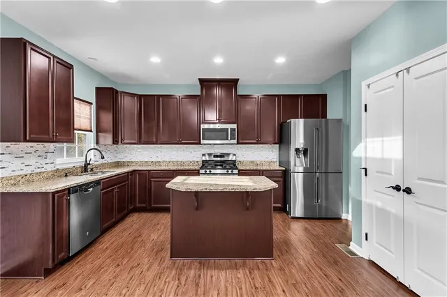a kitchen with kitchen island granite countertop stainless steel appliances a sink cabinets a refrigerator and a sink