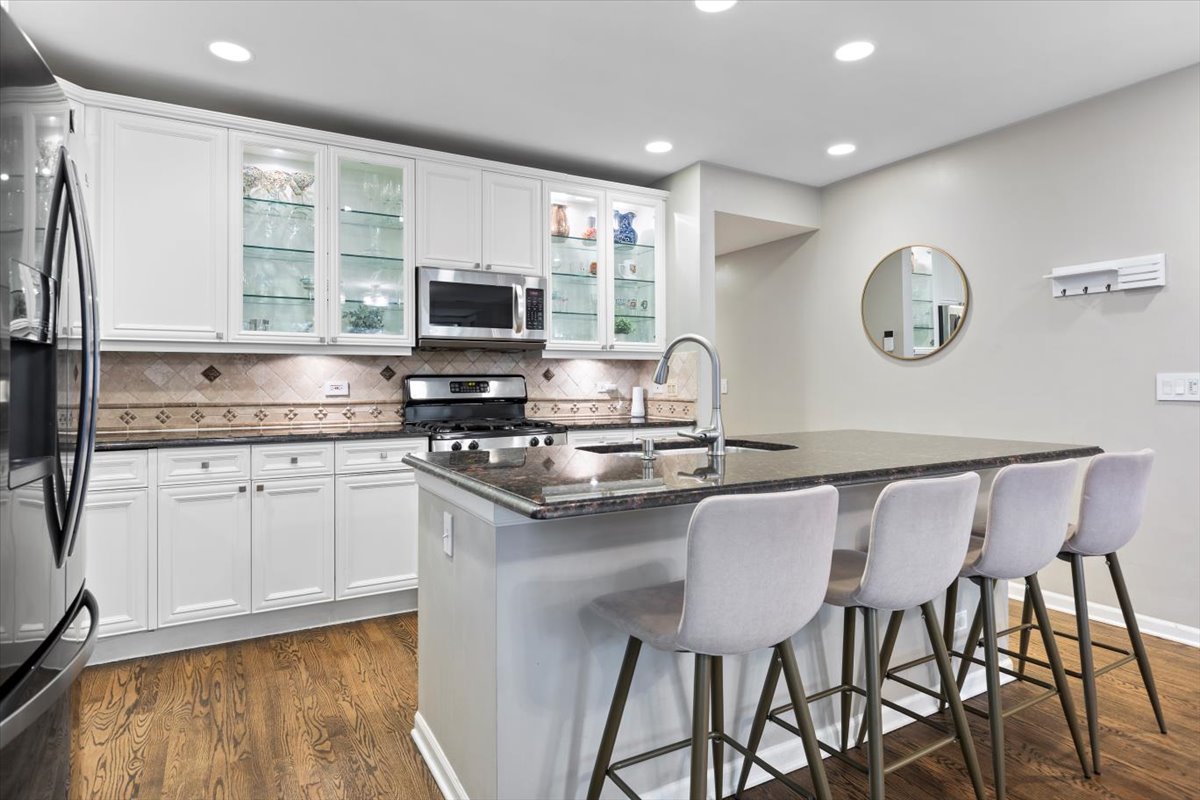 1132 West Wolfram Street, Unit 3 Chicago, IL 60657 - Photo 10 of 26 a kitchen with a dining table chairs cabinets and stainless steel appliances