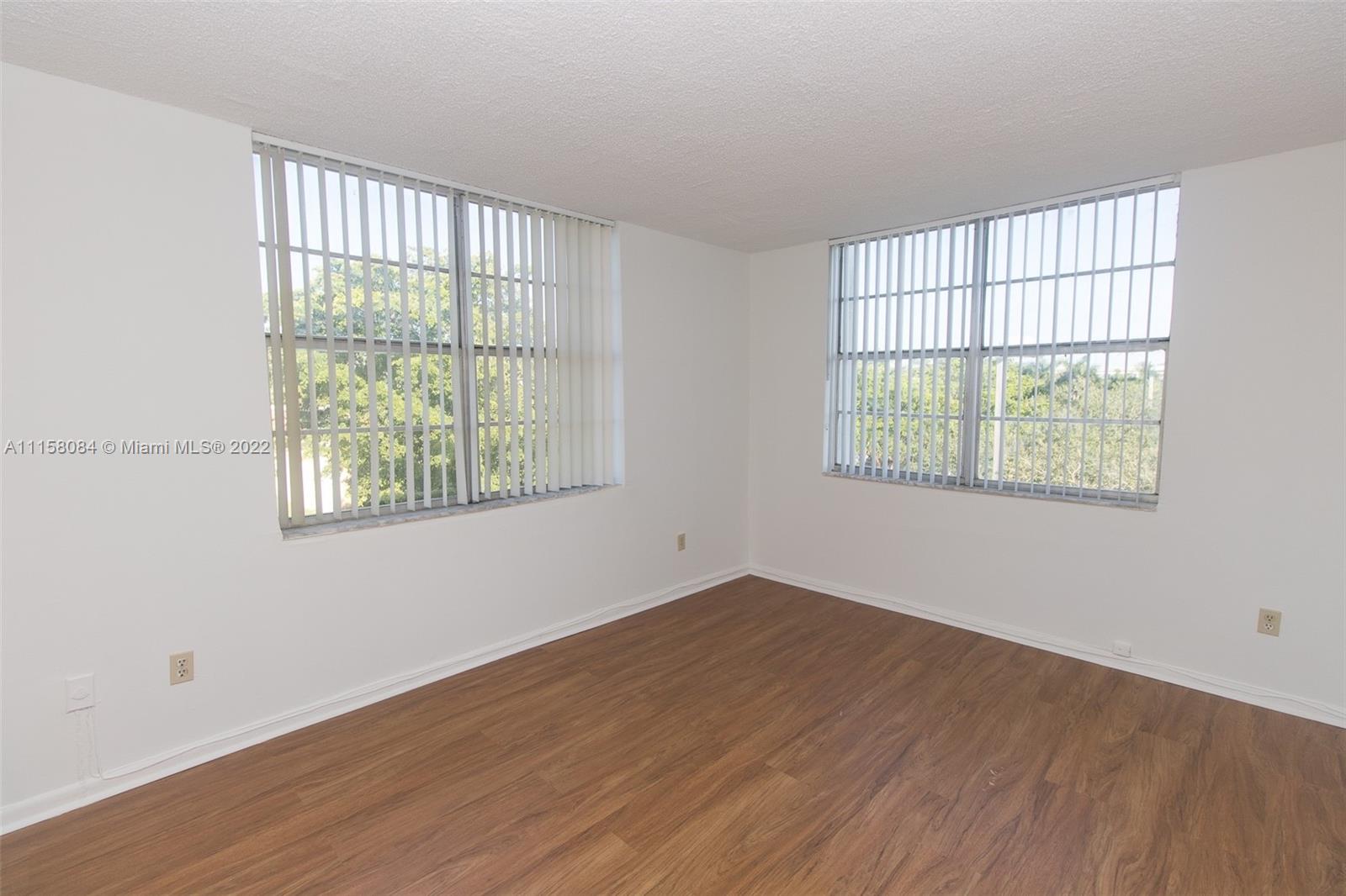 498 Northwest 165th Street, Unit D402 Miami, FL 33169 - Photo 2 of 3 an empty room with wooden floor and windows